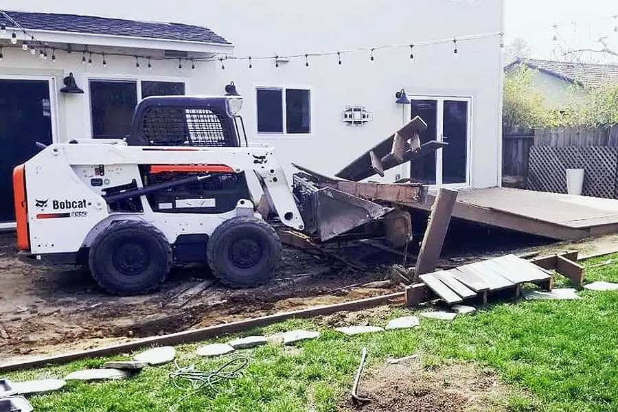 Skid steer tearing out an old backyard deck